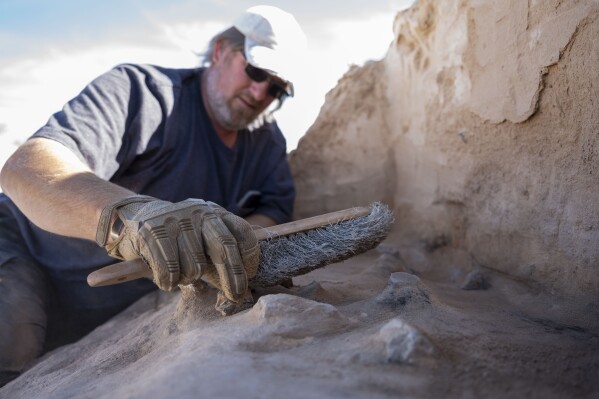 This photo provided by the U.S. Air Force shows Matthew Cuba, 49th Civil Engineer Squadron cultural resource manager, as he brushes off the remnants of a Paleo-Archaic hearth at Holloman Air Force Base, N.M., March 7, 2024. (Airman 1st Class Isaiah Pedrazzini/U.S. Air Force via AP)