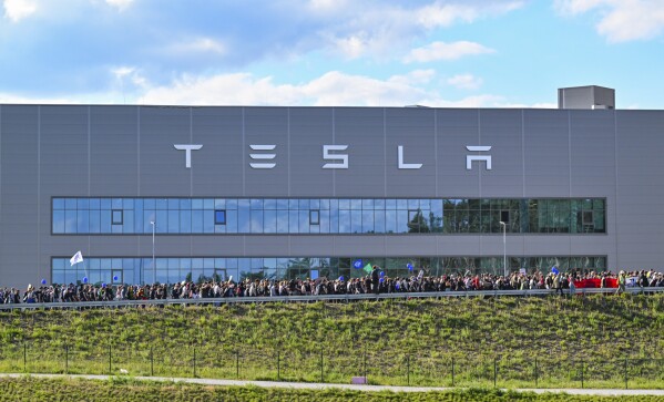 FILE - Demonstrators walk past the Tesla factory in Gruenheide, Germany, May 11, 2024, at the end of their protest. A local council in Germany on Friday May 17, 2024, approved a plan by electric carmaker Tesla to expand the grounds of its first plant in Europe, which has drawn persistent protests this year. (Patrick Pleul/dpa via AP, File)