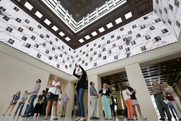 FILE - Visitors to the George W. Bush Presidential Library and Museum look upwards at a 360 degree video screen showing a video welcoming them to the center in Dallas, on May 1, 2013. Concern for U.S. democracy amid deep national polarization has prompted the entities supporting 13 presidential libraries dating back to Herbert Hoover to call for a recommitment to the country's bedrock principles, including the rule of law and respecting a diversity of beliefs. (AP Photo/Tony Gutierrez, File)