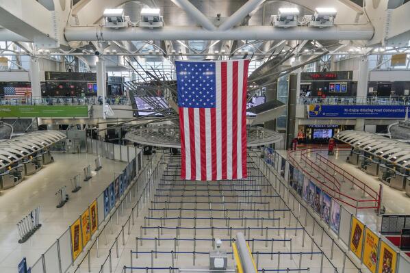 FILE — An American flag hangs over a mostly empty Terminal 1 at John F. Kennedy International Airport in New York, Feb. 17, 2023. Work crews have fixed a power outage at the airport that forced some flights to be canceled or diverted, officials said Saturday, Feb. 18, 2023. (AP Photo/Seth Wenig, File)