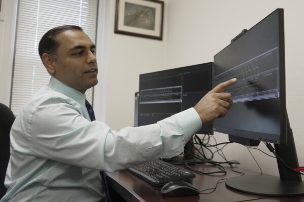 Dr. Roneil Malkani shows an example of pink noise being used to enhance slow brainwaves during deep sleep at the Center for Circadian & Sleep Medicine at Northwestern Medicine in Chicago on May 16, 2024. Pink noise has a frequency profile “very similar to the distribution of brain wave frequencies we see in slow-wave sleep because these are large, slow waves,” said Malkani, assistant professor of neurology at Northwestern University Feinberg School of Medicine. (AP Photo/Laura Bargfeld)