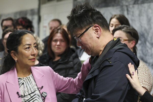 Attorney Karen Koehler, left, comforts plaintiff Bruce Tom during a press conference at the King County Superior Courthouse in downtown Seattle, Wednesday, Jan. 24, 2024. Seattle has agreed to pay $10 million to 50 demonstrators who sued over the police department’s heavy-handed response to racial justice protests in 2020, in a settlement announced by attorneys from both sides. (Kevin Clark/The Seattle Times via AP)