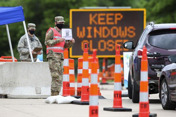 FILE - A National Guard member holds up a sign as vehicles enter a Test Iowa coronavirus testing site at the Kirkwood Community College Continuing Education Training Center in Cedar Rapids, Iowa, on May 28, 2020. State National Guard units are seeing dramatic re-enlistment rates, even as their troops juggle near constant duties with COVID-19, natural disasters and other military deployments. (Rebecca F. Miller/The Gazette via AP, File)