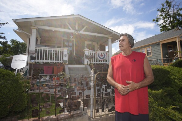 Ben Gallegos stands outside his family's home in the Globeville neighborhood as the daytime high temperature soars toward triple digits, Thursday, July 27, 2023, in north Denver. Gallegos has taken several measures to keep his home cool in spite of lacking central air conditioning. As climate change fans hotter and longer heat waves, breaking record temperatures and leaving dozens dead, the poorest Americans suffer the hottest days with the fewest defenses. Air conditioning, once a luxury, is now a matter of survival. (AP Photo/David Zalubowski)