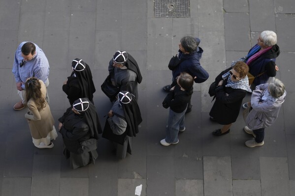 A group of four nuns, center left, wait in line with other people to view Pope Francis lying in state inside St. Peter's Basilica, at the Vatican, Thursday, April 24, 2025. (AP Photo/Markus Schreiber)