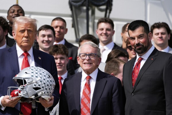 President Donald Trump poses for a photo with Ohio Gov. Mike DeWine, center and head coach Rayan Day as he welcomes the 2025 College Football National Champions, the Ohio State University football team, on the South Lawn of the White House, Monday, April 14, 2025, in Washington. (AP Photo/Alex Brandon)