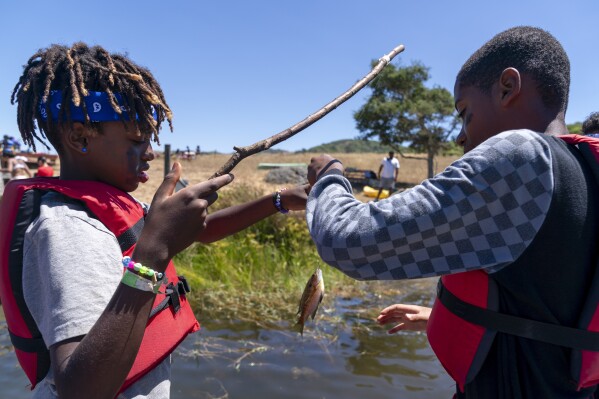 Dressed up for "Pirate Day," Eli, 12, of Phoenix, Ariz., left, and Sasha Wernick, 11, of Brooklyn, catch and release fish during Camp Be'chol Lashon, a sleepaway camp for Jewish children of color, Friday, July 28, 2023, in Petaluma, Calif., at Walker Creek Ranch. (AP Photo/Jacquelyn Martin)