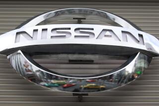 FILE - In this Feb. 8, 2012, file photo, vehicles are reflected on the logo of the Nissan Motors Co. at a showroom in Tokyo's Ginza shopping district. Nissan says its huge factory in Smyrna, Tennessee, will close for two weeks starting Monday, Aug. 16, 2021 due to computer chip shortages brought on by a coronavirus outbreak in Malaysia. (AP Photo/Shizuo Kambayashi, File)