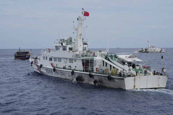 FILE - A Chinese coast guard ship tries to block the way of a Philippine supply boat, left, as it heads towards Second Thomas Shoal, locally known as Ayungin Shoal, at the disputed South China Sea on Aug. 22, 2023. Philippine officials on Monday, Sept. 25 condemned a floating barrier laid by Chinese coast guard vessels to prevent Filipino fishermen from entering a disputed lagoon in the South China Sea and said they would take actions to remove the obstruction. (AP Photo/Aaron Favila, File)