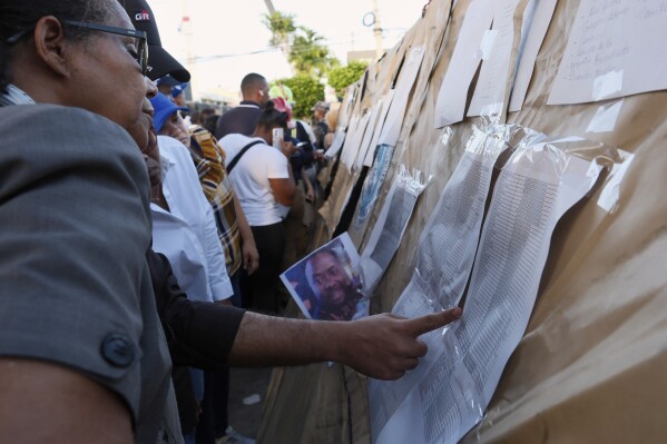 People searching for their missing relatives peruse a list of names outside the Jet Set nightclub after its roof collapsed during a merengue concert in Santo Domingo, Dominican Republic, Tuesday, April 8, 2025. (AP Photo/Ricardo Hernandez)
