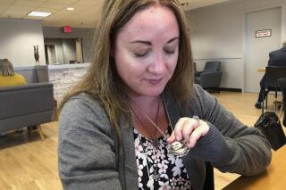 Lori Alhadeff shows a pendant bearing a photo of her 14-year-old daughter Alyssa, among the 17 people killed during the 2018 massacre at Marjory Stoneman Douglas, Friday, March 6, 2020, at the state Capitol in Tallahassee, Fla. Alhadeff has been championing a bill to require all public schools across Florida to put in place a panic button system to give schools a direct link with first responders. (AP Photo/Bobby Caina Calvan)