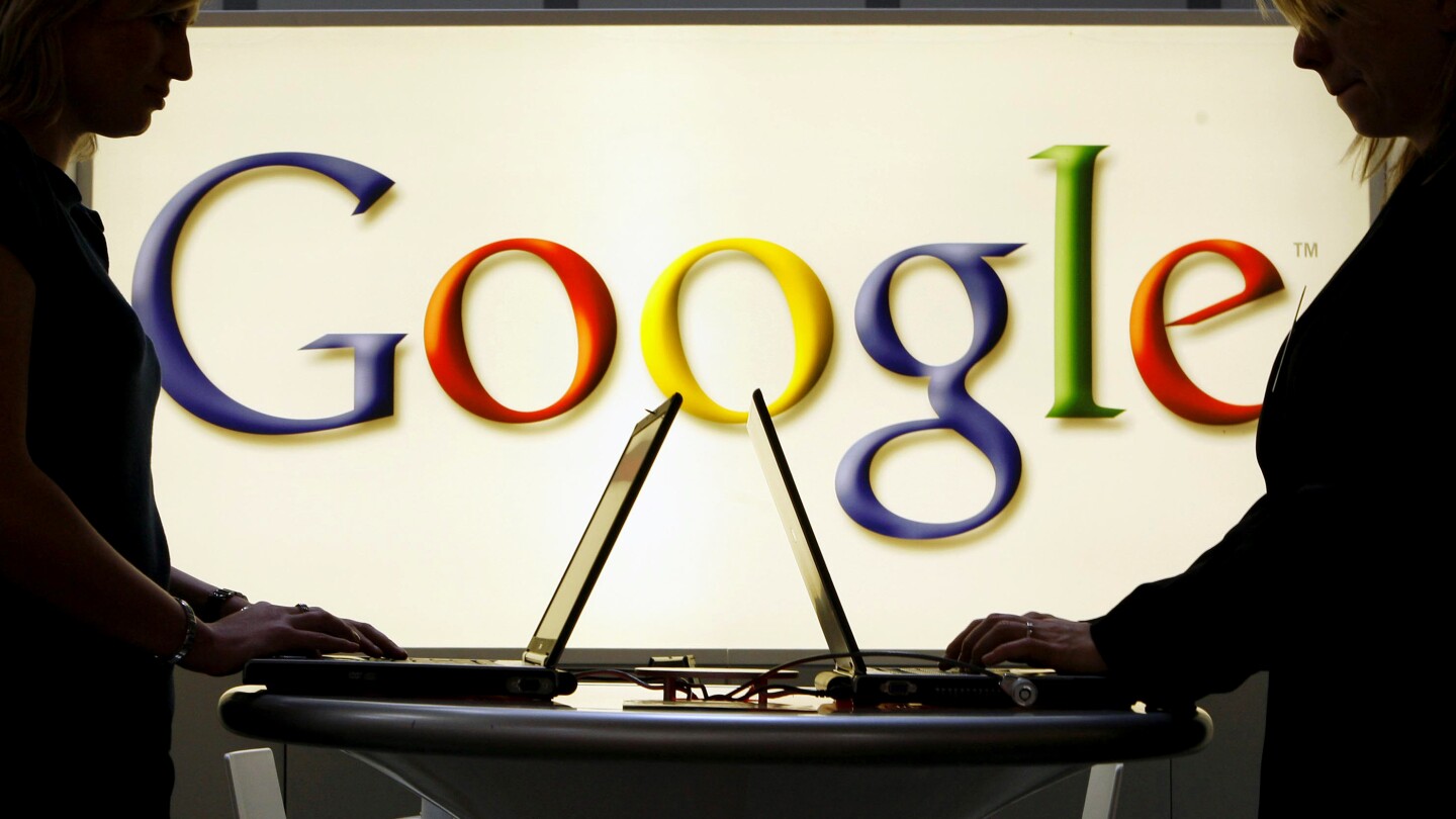 FILE - In this April 17, 2007 file photo, exhibitors work on laptop computers in front of an illuminated sign of the Google logo at the industrial fai