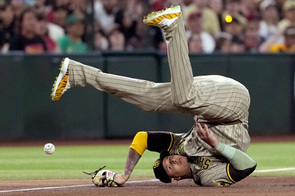 San Diego Padres' Manny Machado falls after stopping a base hit by Arizona Diamondbacks' Lourdes Gurriel Jr. during the sixth inning of a baseball game, Saturday, May 4, 2024, in Phoenix. (AP Photo/Matt York)