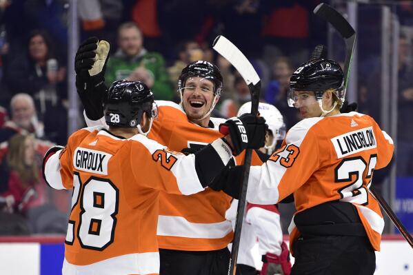Philadelphia Flyers' Justin Braun, center, celebrates his goal with Claude Giroux, left, and Oskar Lindblom during the second period of an NHL hockey game against the New Jersey Devils, Tuesday, Dec. 14, 2021, in Philadelphia. (AP Photo/Derik Hamilton)