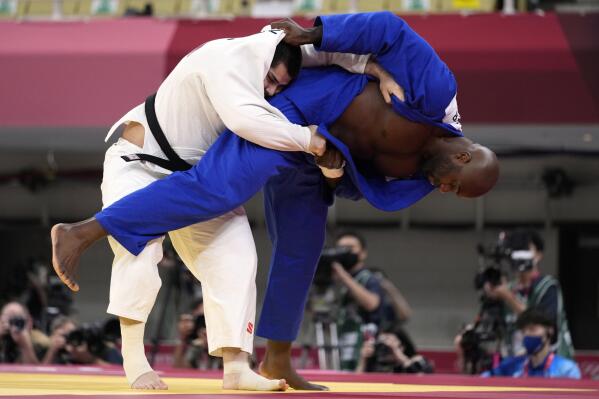 Tamerlan Bashaev of the Russian Olympic Committee, left, and Teddy Riner of France compete during their men's +100kg elimination round judo match at the 2020 Summer Olympics, Friday, July 30, 2021, in Tokyo, Japan. (AP Photo/Vincent Thian)