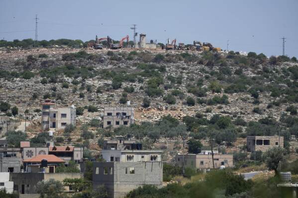 Bulldozers work by an Israeli settlers outpost, near the Israeli settlement of Bruchin, on top of a hill and overlooking the adjacent West Bank village of Bruqin, that was under attack by Israeli settlers overnight and left several burnt vehicles and damaged homes, residents said, near Salfit, Friday, May 23, 2025. (AP Photo/Nasser Nasser)