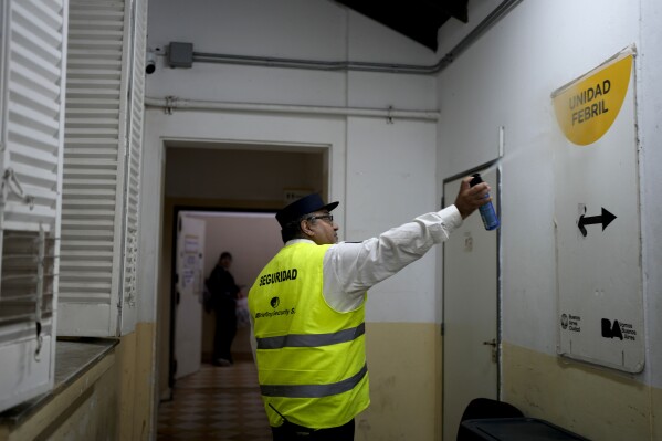 A guard sprays insecticide inside a hospital area where patients with dengue symptoms wait to be attended in Buenos Aires, Argentina, Friday, April 5, 2024. A nationwide increase in dengue fever cases as resulted in the demand for repellents to avoid the bite of the mosquito that transmits the disease, causing a shortage and exorbitant prices where available. (AP Photo/Natacha Pisarenko)