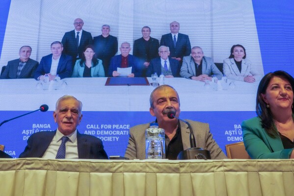 Pro-Kurdish Peoples' Equality and Democracy Party, or DEM, delegation members release an statement from the jailed leader of the rebel Kurdistan Workers' Party, or PKK, Abdullah Ocalan, center at the background photo, in Istanbul, Turkey, Thursday, Feb. 27, 2025. (AP Photo/Khalil Hamra)