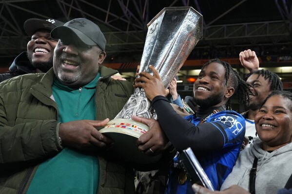 Atalanta's Ademola Lookman celebrates with family members holding the trophy after his team won the Europa League final soccer match between Atalanta and Bayer Leverkusen at the Aviva Stadium in Dublin, Ireland, Wednesday, May 22, 2024. (AP Photo/Kirsty Wigglesworth)
