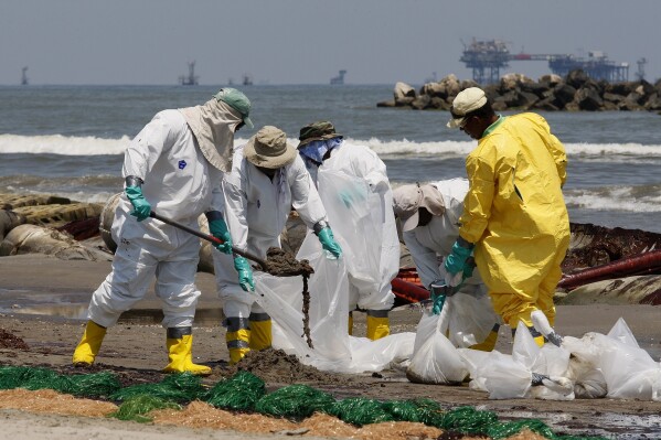 FILE - Workers shovel oil that washed up from the deadly explosion of the Deepwater Horizon oil rig on Fourchon Beach in Port Fourchon, La., May 24, 2010. (AP Photo/Patrick Semansky, File)