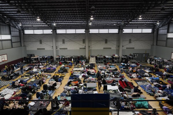 FILE - Ukrainian refugees wait in a gymnasium, April 5, 2022, in Tijuana, Mexico. Some 110 million people around the world have had to flee their homes because of conflict, persecution, or human rights violations, the U.N. High Commissioner for Refugees says. Last year alone, an additional 19 million people were forcibly displaced including more than 11 million who fled Russia's full-scale invasion of Ukraine in what became the fastest and largest displacement of people since World War II. (AP Photo/Gregory Bull, File)