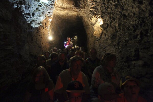 Tour Guide Kyle Burkwit leads a group on the boat section during a tour of the Lockport Caves in Lockport, N.Y., on Aug. 21, 2014. A boat carrying hospitality workers capsized Monday, June 12, 2023, during a tour of the historic underground cavern system built to carry water from the Erie Canal beneath the western New York city of Lockport, killing one person who became trapped beneath the overturned vessel, officials said. (Mark Mulville/The Buffalo News via AP)