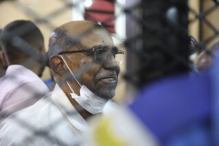 FILE - In this Sept. 15, 2020 file photo, Sudan's ousted president Omar al-Bashir sits at the defendant's cage during his trial a courthouse in Khartoum, Sudan, Tuesday, Sept. 15, 2020. The officer of Sudan’s prime minister says International Criminal Court Prosecutor Fatou Bensouda is arriving in Khartoum Saturday, Oct. 17, to discuss cooperation with local authorities over the trial of those internationally wanted over war crimes and genocide in the Darfur conflict. Among those wanted by the court is former President Omar al-Bashir. (AP Photo/Marwan Ali)