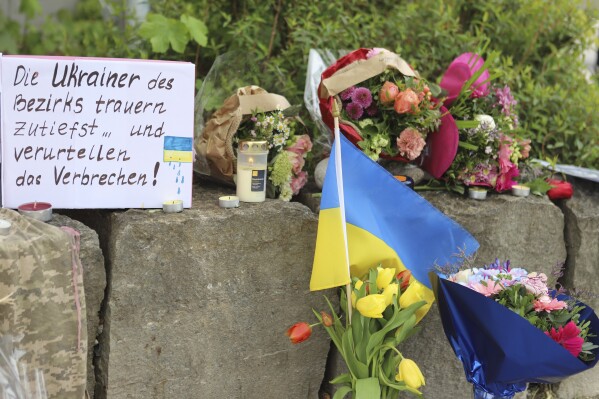 Flowers and a small Ukrainian flag are laid at a shopping center in Murnau, Germany, Sunday, April 28, 2024. Police say two Ukrainian men have been stabbed to death in southern Germany and a Russian man was arrested by authorities as a possible suspect in the killings. German news agency dpa reported Sunday that the two Ukrainians, who were 23 and 36 years old and lived in the southern German county of Garmisch-Partenkirchen, were killed on the premises of a shopping center in the village of Murnau in Upper Bavaria. (Constanze Wilz/dpa via AP)