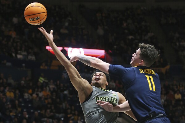 Baylor guard RayJ Dennis, left, is defended by West Virginia forward Quinn Slazinski (11) during the first half of an NCAA college basketball game Saturday, Feb. 17, 2024, in Morgantown, W.Va. (AP Photo/Kathleen Batten)