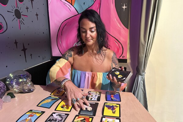 Ashley Branton lays out tarot cards in the back of her shop, Velvet Witch, in Norfolk, Va., Thursday, June 13, 2024. The city of Norfolk recently repealed its 45-year-old ban on “the practice of palmistry, palm reading, phrenology or clairvoyance, for monetary or other compensation.” The 1979 ordinance was not being enforced, however, and the psychic services industry is growing. (AP Photo/Ben Finley)