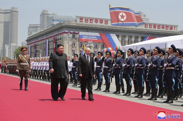 In this photo provided Thursday, June 20, 2024, by the North Korean government, Russian President Vladimir Putin, center, and North Korea's leader Kim Jong Un, center left, review an honor guard during the official welcome ceremony in the Kim Il Sung Square in Pyongyang, North Korea, Wednesday, June 19. The content of this image is as provided and cannot be independently verified. Korean language watermark on image as provided by source reads: 