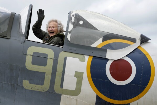 Dorothea Barron, aged 99, who was a serving Wren at the time of D-Day waves as she sits in a Spitfire at Biggin Hill Airport in Kent, England, Tuesday, May 28, 2024. The Taxi Charity for Military Veterans took WWII veterans, including Normandy veterans, to an event at the Biggin Hill Heritage Hangar just ahead of their trip to Normandy for the D Day 80th Anniversary. (AP Photo/Kirsty Wigglesworth)