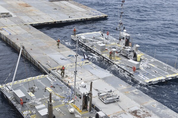 In this image provided by the U.S. Army, soldiers assigned to the 7th Transportation Brigade (Expeditionary) and sailors attached to the MV Roy P. Benavidez assemble the Roll-On, Roll-Off Distribution Facility (RRDF), or floating pier, off the shore of Gaza in the Mediterranean Sea on April 26, 2024. The pier is part of the Army's Joint Logistics Over The Shore (JLOTS) system which provides critical bridging and water access capabilities. (U.S. Army via AP)