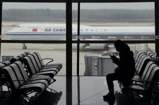 FILE - A passenger checks her phone as an Air China passenger jet taxi past at the Beijing Capital International airport in Beijing, Saturday, Oct. 29, 2022. The Chinese air travel regulator is preparing to allow airlines to fly more routes between China and the United States following the lifting of anti-virus travel restrictions, state TV reported Wednesday, Jan. 11, 2023. (AP Photo/Ng Han Guan, File)