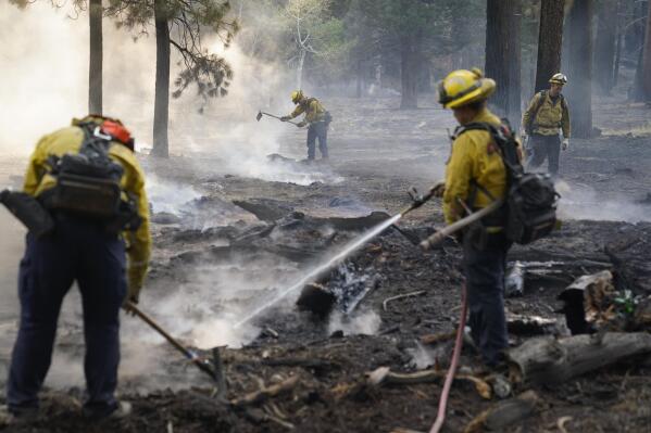 Firefighters put out hot spots near South Lake Tahoe, Calif., Wednesday, Sept. 1, 2021. Authorities are reporting progress in the battle to save communities on the south end of Lake Tahoe from a huge forest fire. (AP Photo/Jae C. Hong)