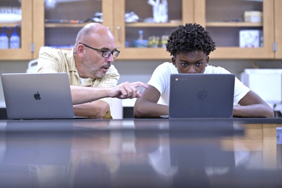 History teacher Matt Brophy, left, works with Flerentin “Flex” Jean-Baptiste, 16, of Medford, Mass., on making up late assignments during summer school at Medford High School, Friday, Aug. 2, 2024, in Medford. (AP Photo/Josh Reynolds)