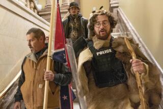 FILE — Supporters of President Donald Trump, including Aaron Mostofsky, right, who is identified in his arrest warrant, walk down the stairs outside the Senate Chamber in the U.S. Capitol, in Washington, Jan. 6, 2021. Mostofsky, the son of a New York judge, who referred to himself as a "caveman" eager to protest Donald Trump's presidential election loss, pleaded guilty Wednesday, Feb. 2, 2022, to charges he stormed the U.S. Capitol during the Jan. 6, 2021, insurrection. (AP Photo/Manuel Balce Ceneta, File)