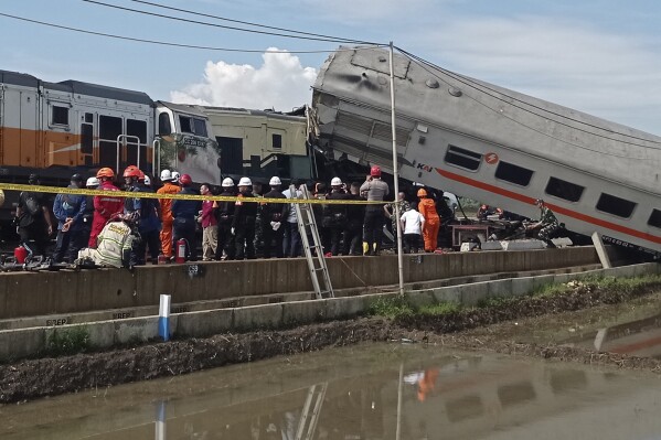 Rescuers inspect the wreckage of trains after a collision in Cicalengka, West Java, Indonesia, Friday, Jan. 5, 2024. The two trains collided on Indonesia's main island of Java on Friday, causing several carriages to buckle and overturn, officials said. (AP Photo/Abdan Syakura)