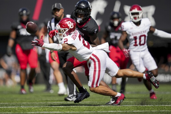 Oklahoma defensive back Billy Bowman Jr. (2) intercepts a pass intended for Cincinnati wide receiver Dee Wiggins, back, during the second half of an NCAA college football game, Saturday, Sept. 16, 2023, in Cincinnati. (AP Photo/Aaron Doster)