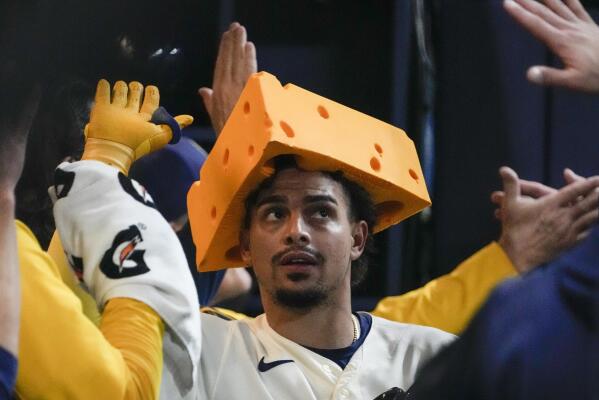 Milwaukee Brewers' Willy Adames, right, places a cheesehead hat on