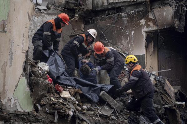 Rescue workers transfer the body of a man killed in a Russian missile strike on an apartment building, into a plastic bag in the southeastern city of Dnipro, Ukraine, Monday, Jan. 16, 2023. (AP Photo/Evgeniy Maloletka)