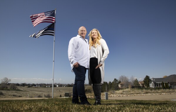 Jennifer and Tim Kohl poses for a photo in their front yard with the American flag and a thin blue line flag in Star, Idaho, on April 14, 2023. The couple recently moved to Idaho from the Los Angeles area. Americans are segregating by their politics at a rapid clip, helping fuel the greatest divide between the states in modern history. (AP Photo/Kyle Green)