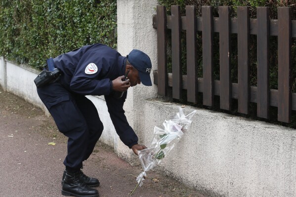 FILE - A French police officer lays flowers while paying tribute to his colleagues killed in a knife attack near their home in Magnanville, west of Paris, France, on June 14, 2016. A trial is opening in French counterterrorism court Monday Sept. 25, 2023 over the killing of two police officers in their home in 2016, in front of their 3-year-old son. (AP Photo/Thibault Camus, File)