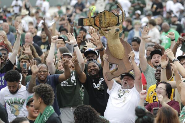 Kirk Carley, of Milwaukee, right, holds up a deer statue during a parade celebrating the Milwaukee Bucks' NBA Championship basketball team Thursday, July 22, 2021, in Milwaukee. (AP Photo/Aaron Gash)
