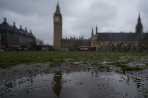 Rain falls into a puddle in Parliament Square, with a backdrop of the Houses of Parliament, in London, Friday, May 3, 2024. A High Court judge ruled Friday that Britain's government acted unlawfully when it approved a plan to meet the U.K.'s climate targets without evidence it could be delivered. It was the second time in two years that the government's main climate action plan was found unlawful and insufficient in meeting targets to cut greenhouse gas emissions. (AP Photo/Kin Cheung)