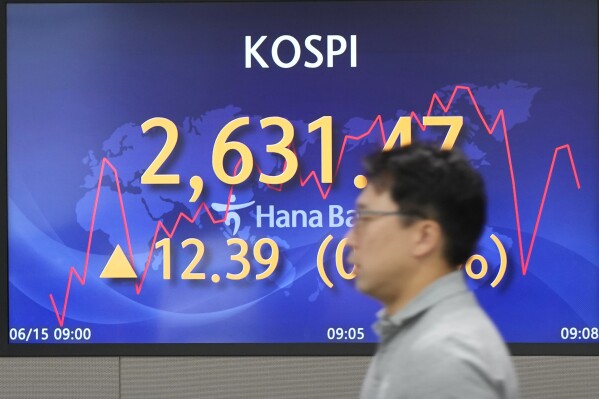 A currency trader walks by the screen showing the Korea Composite Stock Price Index (KOSPI) at a foreign exchange dealing room in Seoul, South Korea, Thursday, June 15, 2023. Asian shares were mostly higher Thursday after the U.S. Federal Reserve held interest rates steady while hinting more hikes may be coming. (AP Photo/Lee Jin-man)