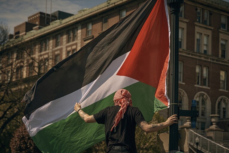 A protester places a Palestinian flag at a pro-Palestinian encampment at Columbia University, in New York, Sunday, April 28, 2024, advocating for financial disclosure and divestment from all companies tied to Israel and calling for a permanent cease-fire in Gaza. (AP Photo/Andres Kudacki)