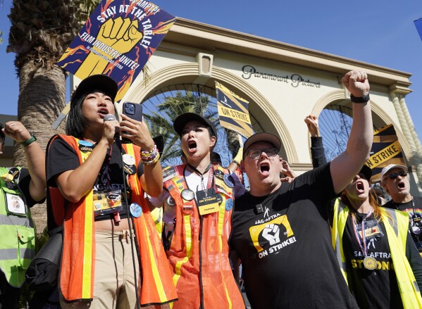 From left; SAG-AFTRA captains Iris Liu and Miki Yamashita and SAG-AFTRA chief negotiator Duncan Crabtree-Ireland lead a cheer for striking actors outside Paramount Pictures studio, Friday, Nov. 3, 2023, in Los Angeles. (AP Photo/Chris Pizzello)