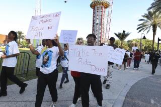 FILE - Family and supporters of Tyre Sampson march and hold signs outside the Orlando Free Fall drop tower ride at ICON Park in Orlando on March 29, 2022. A towering amusement ride in central Florida's tourism district where Tyre, 14, died when he fell to his death will be taken down because of the accident, the owner said Thursday, Oct. 6, 2022. (Stephen M. Dowell/Orlando Sentinel via AP, File)