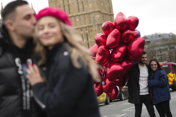 Couples pose for a photograph during the Valentine's Day in London, Wednesday, Feb. 14, 2024. (AP Photo/Kin Cheung)